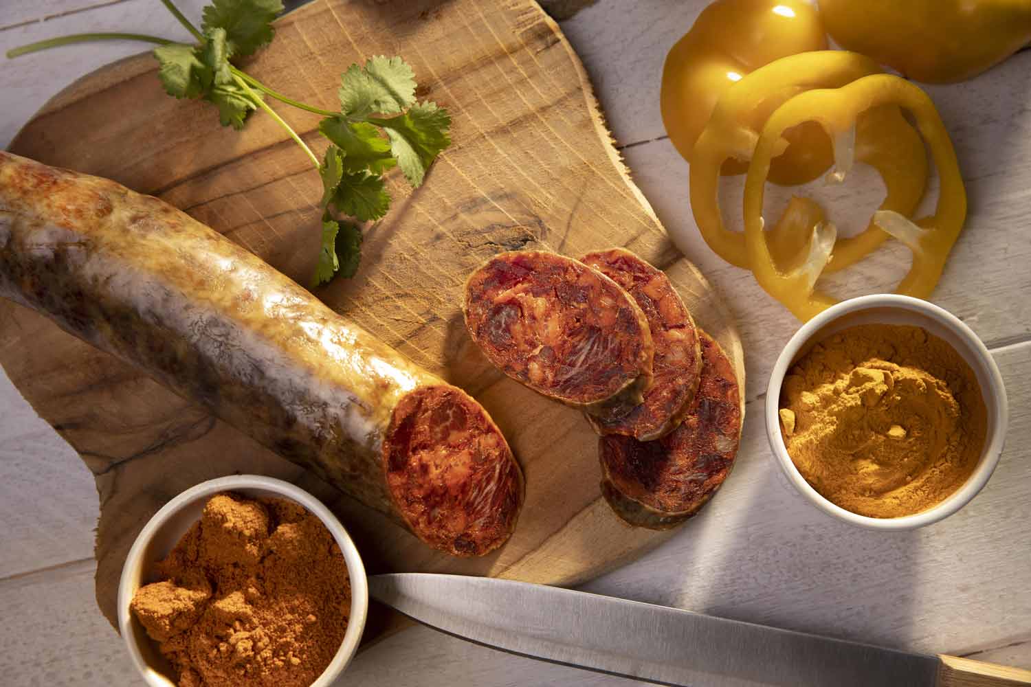 Chorizo artesanal espa&ntilde;ol cortado en tabla con cuchillo